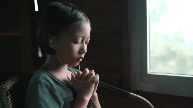 Child girl praying on bible with light in morning at home, christian concept. High quality 4k video.
