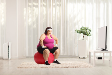 Overweight woman sitting on a fintess ball and thinking