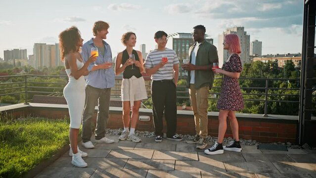 Men and women talking and drinking during party on rooftop