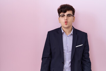 Fototapeta premium Young non binary man with beard wearing suit and tie making fish face with lips, crazy and comical gesture. funny expression.