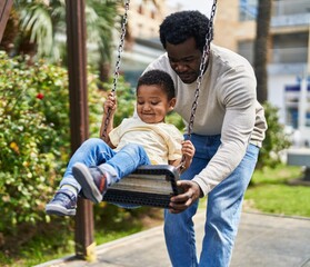 Father and son playing on swing at playground