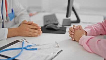 Man and woman doctor and patient sitting on table at the clinic