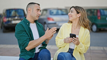 Man and woman couple using smartphone smiling at street