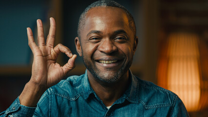 Close-up happy mature african american man showing ok sign approval gesture satisfied smiling ethnic male demonstrating recommendation symbol good mood success excellent result looking camera at home
