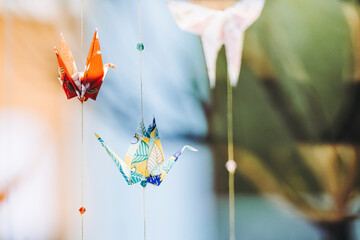 Origami fabriqué en papier coloré suspendu en forme d'oiseau grue japonaise  - obrazy, fototapety, plakaty