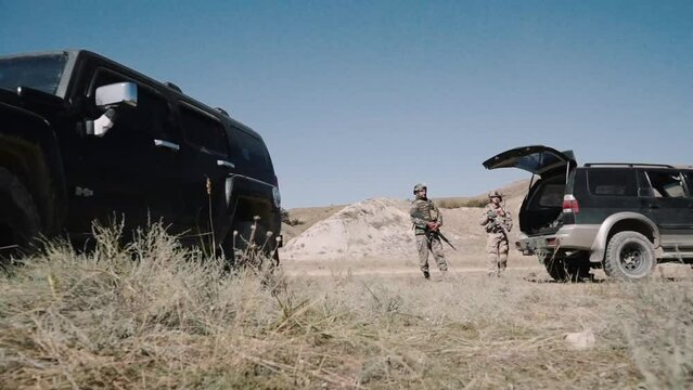 desert terrain. stands an armed soldier with a machine gun