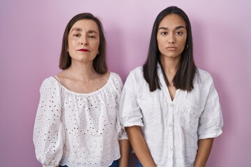 Hispanic mother and daughter together relaxed with serious expression on face. simple and natural looking at the camera.