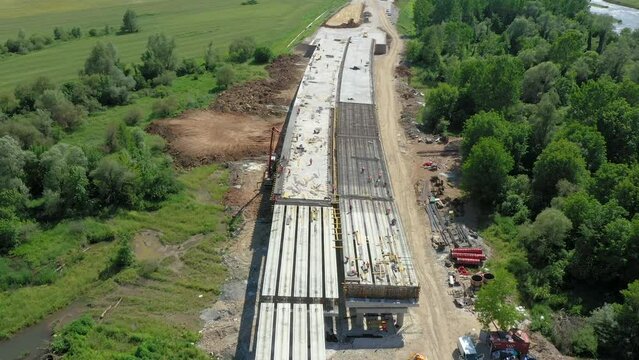 Highway bridge under construction. Infrastructure at a motorway road construction site. Freeway being built on a mountain terrain. Aerial view of new highway construction site with overpass section