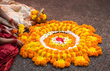 Kerala girls celebrating Onam festival and making Onam pookalam with decorating flowers on the floor, Happy Onam concept image