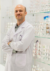 Male optician and optometrist with digital tablet on background of shop window with different models of glasses