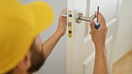 Young hispanic man repairing knob door at home