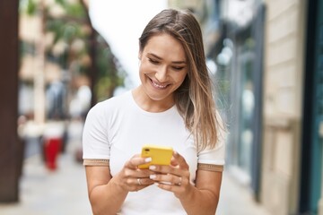 Young caucasian woman smiling confident using smartphone at street