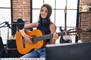 Adorable girl musician singing song playing classical guitar at music studio