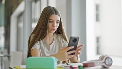 Young beautiful girl student using smartphone looking upset at library