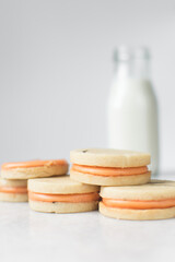 Vanilla sugar cookies with orange filling, round rosemary cookies filled with orange cream, no spread cookies on a marble tray with a white background