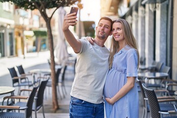 Man and woman couple expecting baby make selfie by smartphone at coffee shop terrace