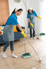 Asia woman in workwear maid sweep up construction debris with a brush in a dustpan at home	