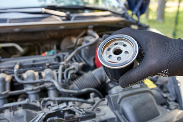 The old clogged oil filter is replaced with a new one. Car repair and maintenance.