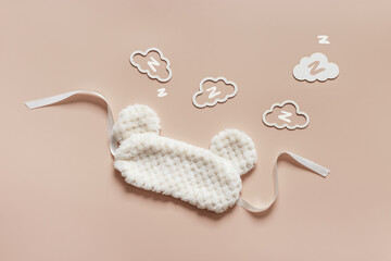 Sleep mask from soft nice fur and clouds shape with z snore sounds  on beige background. Light Fluffy eye cover mask for best sleep. Concept of travel comfort, dream well, rest at night, Minimal