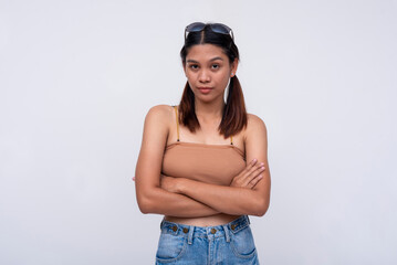 A young asian woman looking unimpressed, crossing her arms. Isolated on a white background.