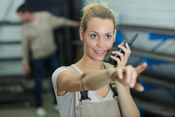 young female worker giving instructions via walkie talkie