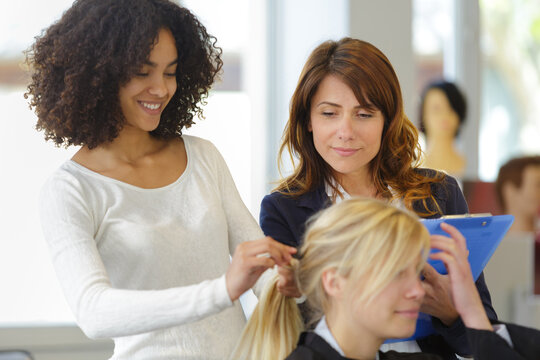 apprentice cutting hair while instructor is watching