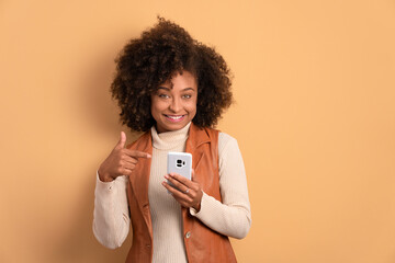 happy african american woman smiling and holding mobile phone in all beige colors. network,...