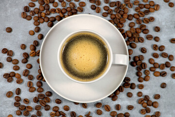 Fresh coffee in cup with coffee bean and gray background. Black coffee in cup with coffee beans...