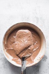 Chocolate cake batter on a black spatula, folding cake batter using a silicone spatula, the process of making chocolate cake