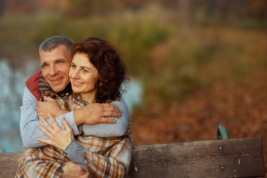 happy romantic couple in park embracing while sitting on bench - Powered by Adobe