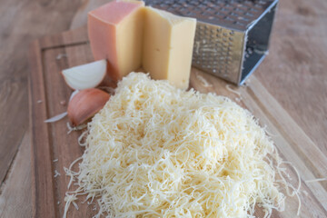 käse gerieben mit reibe auf holzbrett 