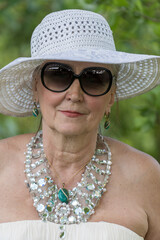 Portrait of a happy elderly woman 65 - 70 years old in a straw hat on the background of nature, closeup