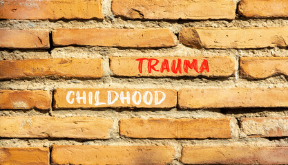 Childhood trauma symbol. Concept words Childhood trauma on beautiful brick wall. Beautiful red...