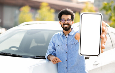 Happy young indian man standing by auto, showing phone