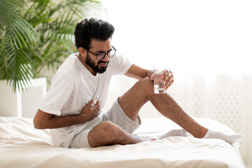 Indian Man Suffering Sudden Chest Pain While Sitting In Bed At Home