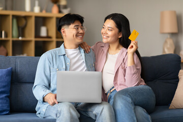 Fototapeta premium Korean Couple Shopping Online Using Laptop And Credit Card Indoor