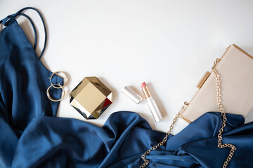 Women’s accessories, handbag and cocktail dress in blue are on a light background. Copy space.