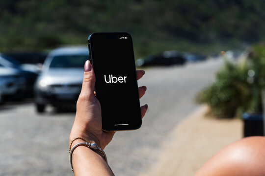 Girl on the street holding smartphone with Uber app on the screen waiting for car to arrive. Rio de Janeiro, RJ, Brazil. August 20 2023