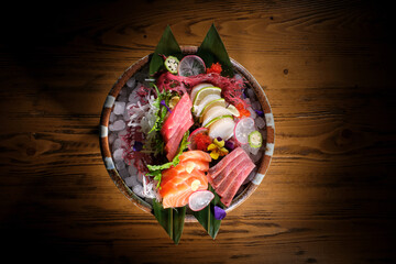 Plate of delicious sashimi with fish and vegetables on wooden ta