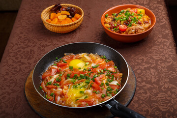 hot shakshuka in a frying pan sprinkled with green onions and chelnt on the sabbath table.