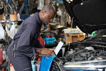 mechanic using laptop computer for checking and fixing a car in automobile repair shop