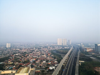 Fototapeta na wymiar Bekasi City with long highway, tall buildings and smog due to air pollution. Poor air quality in the Jabodetabek area. Concept for climate change, global warming.
