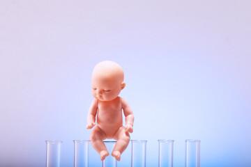 Figurine of a pupa on chemical test tubes. Concept of artificial insemination, test tube baby - obrazy, fototapety, plakaty