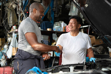 mechanic shaking hands with coworker after fixing a car in automobile repair shop