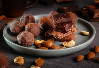 Pieces of chocolate and nuts in a plate on a dark background