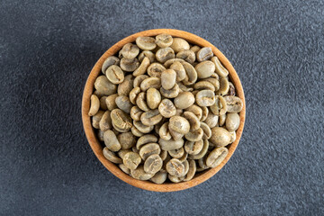 A bowl full of green coffee beans on dark background