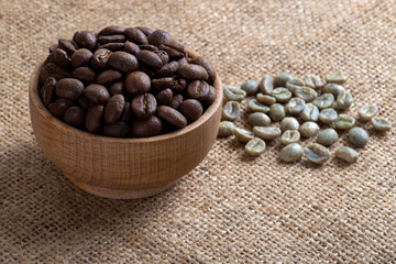 Green coffee with roasted coffee beans on burlap sack,closeup