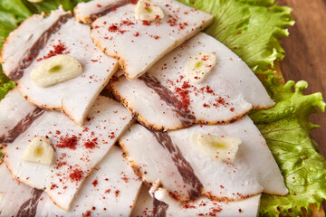 Salo on a wooden board with green salad and garlic, close-up, shallow depth of field