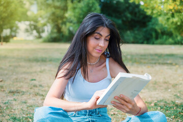 Woman reading a book in the summer park	
