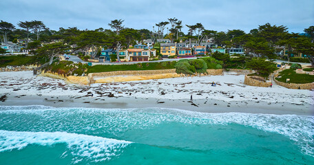 Fototapeta na wymiar Gorgeous turquoise waves crashing against Carmel Beach shore with kelp on white sand aerial